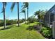 Beautiful backyard view with lush lawn, tall palms, walking path, and screened-in lanai for outdoor living at 4629 Samoset Dr, Sarasota, FL 34241