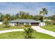 Charming single-story home featuring a landscaped front yard, a circular driveway and a beautiful blue exterior at 4807 W Country Club Dr, Sarasota, FL 34243