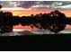 A picturesque pond reflects a vibrant sunset, framed by trees and colorful skies at 5224 88Th E St, Bradenton, FL 34211