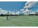 Well-maintained tennis court with green surface, net, and a covered shelter, set against a bright, cloudy sky at 5685 Palmer Cir # 202, Bradenton, FL 34211