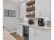 Dry bar with white cabinetry, open wood shelves, and a wine refrigerator at 6600 Horned Owl Pl, Sarasota, FL 34241