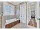 Relaxing bathroom featuring a soaking tub, tiled walls, modern fixtures, and a view of the hallway at 6600 Horned Owl Pl, Sarasota, FL 34241