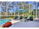 Outdoor screened pool area with blue water, lounge chairs, and an umbrella; lush landscaping outside of enclosure at 7718 Heathfield Ct, University Park, FL 34201