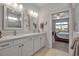 Bright bathroom featuring a double vanity, white cabinetry, modern fixtures, and a view into the bedroom at 8726 Backshore Ln, Parrish, FL 34219