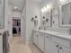 Bright bathroom with double vanity, white cabinetry, modern fixtures, and a view into the walk-in closet at 8726 Backshore Ln, Parrish, FL 34219