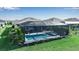 An aerial view of a screened-in pool with a spa, surrounded by lush green landscaping at 8726 Backshore Ln, Parrish, FL 34219