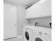 Modern laundry room features front load washer and dryer, storage cabinets and light gray walls at 1155 N Gulfstream Ave # 1205, Sarasota, FL 34236