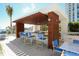Outdoor kitchen with a bar and stools that features a wood pergola, and lush landscaping at 1155 N Gulfstream Ave # 1205, Sarasota, FL 34236