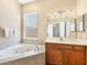 Bright bathroom with a large soaking tub, tiled surround, and wood vanity at 1365 Western Pine Cir, Sarasota, FL 34240