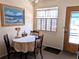 Cozy dining area with round table, three chairs, a painting, and natural light streaming through the window at 1531 Pleasant Rd # H-3, Bradenton, FL 34207