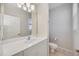 Bathroom featuring a white vanity, toilet, large mirror, and neutral tile flooring at 17809 Howling Wolf Run, Parrish, FL 34219