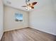 Bright bedroom features wood-look floors, ceiling fan, and window views at 17809 Howling Wolf Run, Parrish, FL 34219