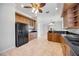 Open-concept kitchen with wood cabinetry, black appliances, tile flooring, and a view of the adjacent room at 17809 Howling Wolf Run, Parrish, FL 34219