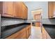 A walk-through butler's pantry showcasing wood cabinets, black countertops, and mosaic tile backsplash at 17809 Howling Wolf Run, Parrish, FL 34219