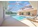 A swimming pool inside a screened enclosure with lounge seating and a tennis court just outside the enclosure at 17809 Howling Wolf Run, Parrish, FL 34219