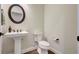 Well-lit half bathroom with pedestal sink, round mirror, and wood-look flooring at 18115 Littleton Pl, Bradenton, FL 34202