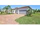 Charming single-story home featuring a paver driveway, a gray garage door, and a well-manicured lawn at 18115 Littleton Pl, Bradenton, FL 34202