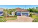 Charming single-story home features lush landscaping with palm trees and a brick driveway leading to a two-car garage at 18115 Littleton Pl, Bradenton, FL 34202
