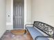 Covered front porch featuring a neutral door, welcome mat, brick floor, and a wrought iron bench at 18115 Littleton Pl, Bradenton, FL 34202