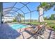 Screened-in pool area with lounge chairs, umbrella, and tropical landscaping at 18115 Littleton Pl, Bradenton, FL 34202