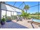 Screened in patio with table and chairs with lush landscaping and pool in the background at 18115 Littleton Pl, Bradenton, FL 34202