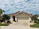 Inviting single-story home featuring a clay tile roof, paver driveway, and lush, mature landscaping at 2160 Chenille Ct, Venice, FL 34292