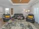 Inviting living room with stylish gray furniture, a patterned rug, and a unique wood plank tray ceiling detail at 2160 Chenille Ct, Venice, FL 34292
