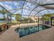 Screened in pool with rock surround, lake view, and mature tropical trees at 2160 Chenille Ct, Venice, FL 34292