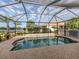 Screened in pool with rock surround, lake view, and mature tropical trees at 2160 Chenille Ct, Venice, FL 34292
