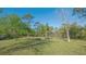 View of a large grassy backyard dotted with trees and surrounded by lush greenery at 2230 Myakka Rd, Sarasota, FL 34240
