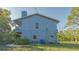 View of the side of a two-story blue home featuring windows, chimney, and a small second story balcony at 2230 Myakka Rd, Sarasota, FL 34240
