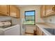 Functional laundry room with front loading washer/dryer, natural wood cabinets and sink at 2230 Myakka Rd, Sarasota, FL 34240