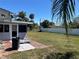 Home backyard featuring large lawn, screen door, and mature trees in the distance at 22337 Olean Blvd, Port Charlotte, FL 33952