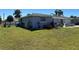 View of backyard with lush lawn, and a glimpse of the home's exterior at 22337 Olean Blvd, Port Charlotte, FL 33952
