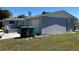 View of the side of the home featuring an attached garage, green waste receptacles, and lawn at 22337 Olean Blvd, Port Charlotte, FL 33952