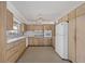 Functional kitchen featuring a white refrigerator, tile floors, and light wood cabinetry at 3466 Tanglewood Dr, Sarasota, FL 34239