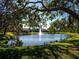 Scenic pond view with a tranquil water fountain surrounded by lush greenery and mature trees at 3922 Wilshire Cir # 177, Sarasota, FL 34238