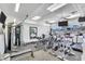 Bright gym with modern exercise equipment, fans, TV, mirror, and natural light from the windows at 4216 El Dorado Cv, Bradenton, FL 34210