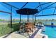 Screened lanai with outdoor seating and lush landscaping by the pool overlooking the water at 4253 Pond Brook Ct, Bradenton, FL 34211