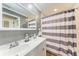 Neutral bathroom with double sinks, chrome fixtures and striped shower curtain at 4283 Southwell Way, Sarasota, FL 34241
