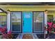 Close-up of a bright blue front door with sidelights and decorative plants at 4283 Southwell Way, Sarasota, FL 34241