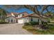 Beautiful two-story home with a red tile roof, a three-car garage and a large shady tree in the front yard at 4404 Calle Serena, Sarasota, FL 34238