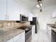 Bright kitchen featuring white cabinetry, stainless steel appliances, and stone countertops at 4453 Meadow Creek Cir, Sarasota, FL 34233