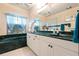 Bathroom featuring a double vanity with green marble countertop, white cabinets, and a large tub under a window at 4464 Mcintosh Lake Ave, Sarasota, FL 34233