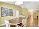 The dining room features yellow walls, an oval table, and bright light fixtures overhead at 4933 Rutland Gate, Sarasota, FL 34235