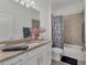 Bathroom featuring granite countertops, a framed mirror, a shower-tub combo with a patterned shower curtain at 5311 White Sand Cv, Bradenton, FL 34211