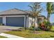 Charming home featuring a gray garage door, gray tile roof, and lush landscaping at 5311 White Sand Cv, Bradenton, FL 34211