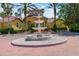 Picturesque clubhouse entrance with a water fountain surrounded by manicured lawns and swaying palm trees at 5401 Bentgrass Dr # 1-302, Sarasota, FL 34235