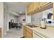 Open kitchen view with wood cabinets, stainless steel sink, and a view of the adjacent dining area at 5401 Bentgrass Dr # 1-302, Sarasota, FL 34235