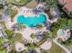 Aerial view of a kidney-shaped community pool surrounded by lounge chairs, palm trees, lush green landscaping and a hot tub at 5401 Bentgrass Dr # 1-302, Sarasota, FL 34235